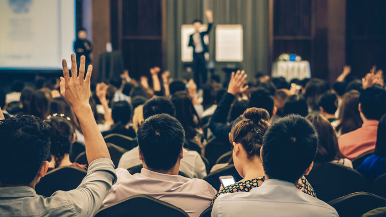 Convention attendees raising hands during a Q&A session