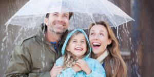Family sheltering under an umbrella during a rainstorm at an outdoor event