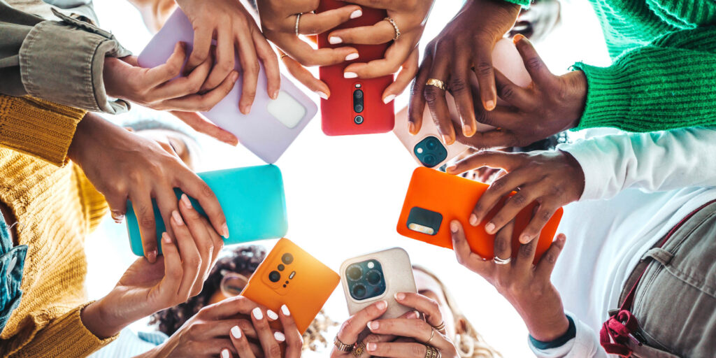 Group of people holding up different phones together, comparing messaging apps