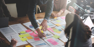 Team planning an event communication plan with sticky notes and schedules spread across a table
